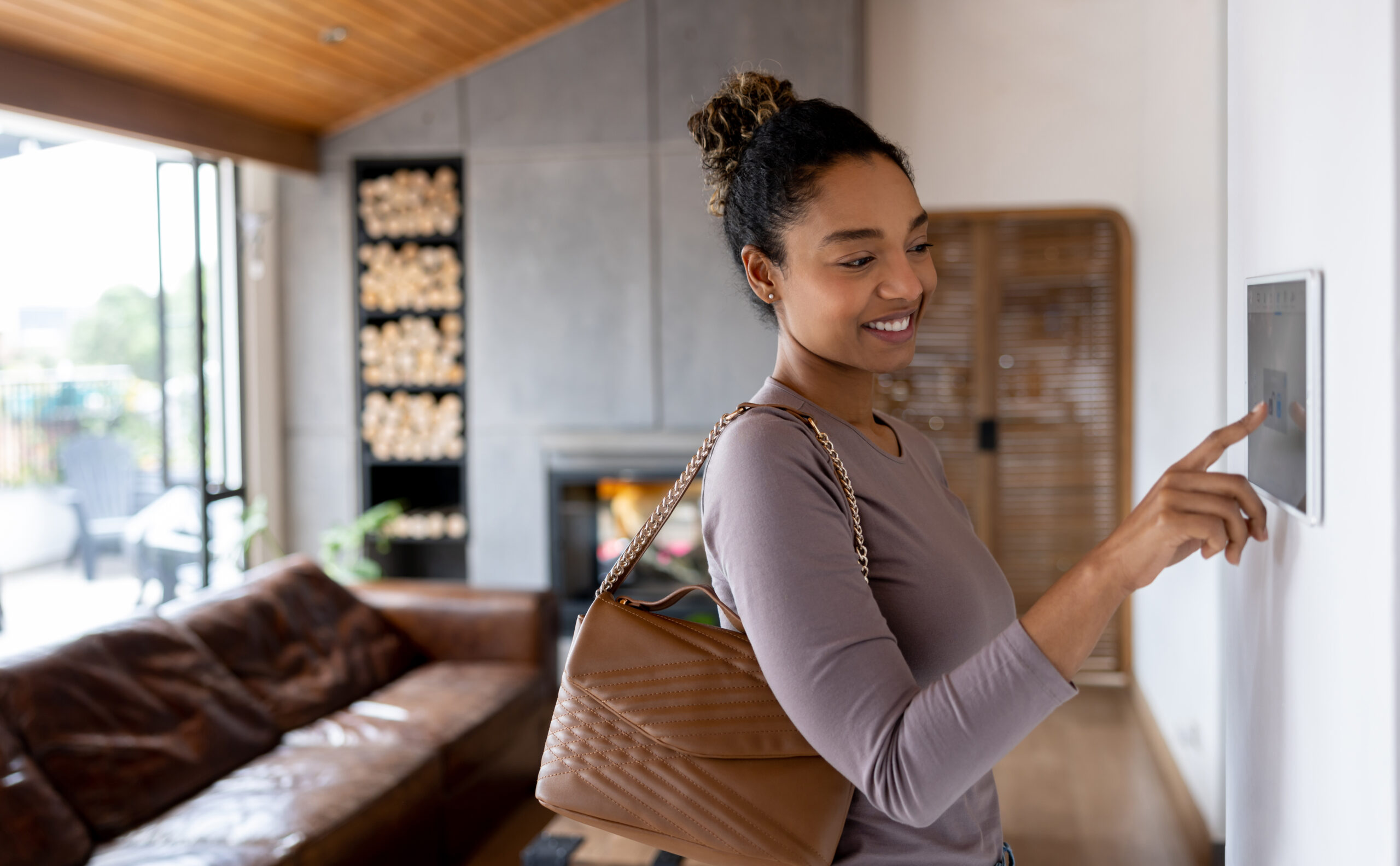 Happy African American woman activating the alarm while leaving her smart home using an automated system.