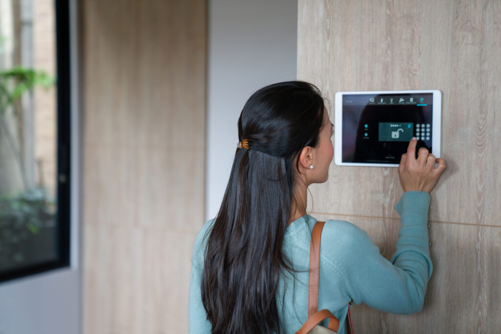 Woman entering pin to lock the door of her house using a home automation system
